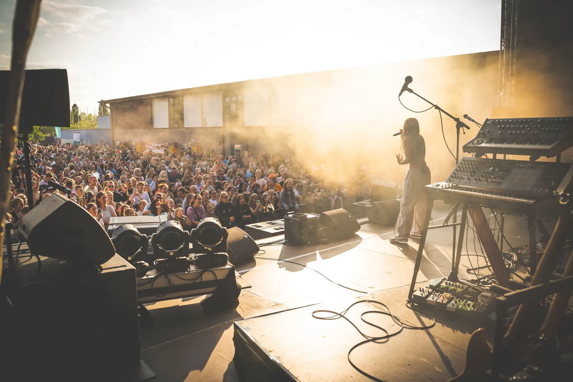 Sängerin auf der Bühne im Gegenlicht, davor ein volles Open-Air-Publikum bei Wismar tanzt 2023